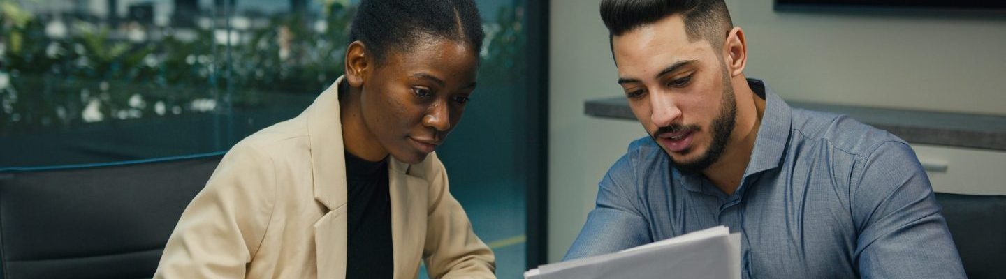 Diverse business colleagues Indian Arabian man and African American woman working discuss financial data analyzing documents corporate paper project result in report with laptop talk at office meeting. High quality photo